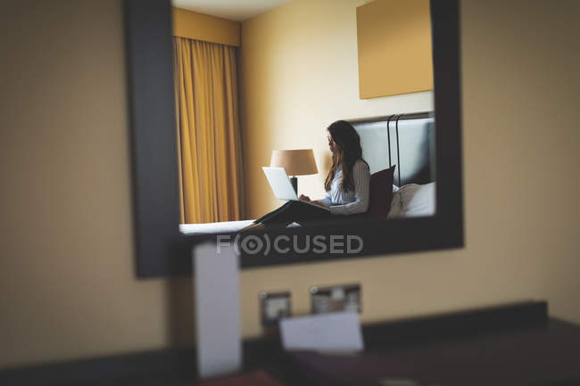 Geschäftsfrau benutzt Laptop auf Bett im Hotelzimmer — Stockfoto