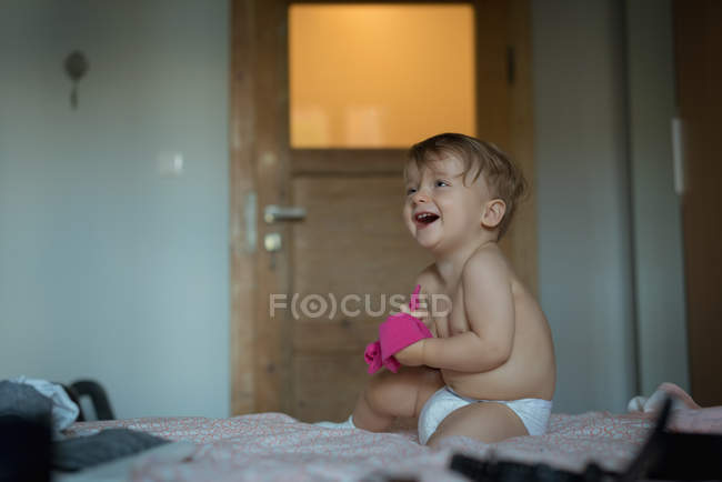 Niño sonriendo en la cama en casa - foto de stock