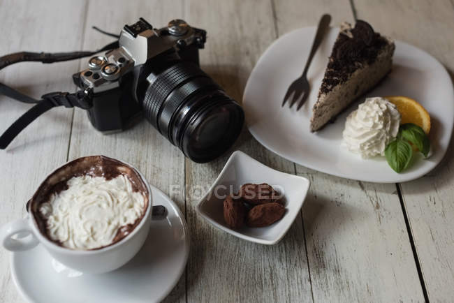 Close-up da câmera e deliciosa comida doce na mesa de madeira — Fotografia de Stock