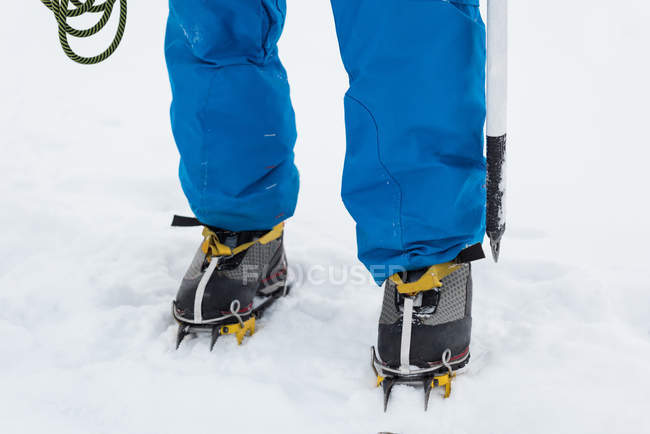 Низька частина чоловічого альпініста, що стоїть на засніженому регіоні взимку — стокове фото