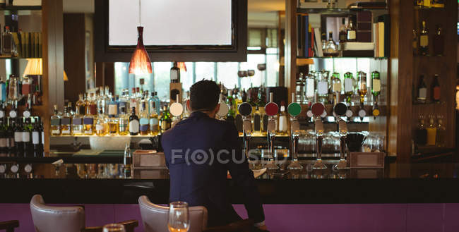 Rear view of businessman having a glass of whisky in hotel — Stock Photo
