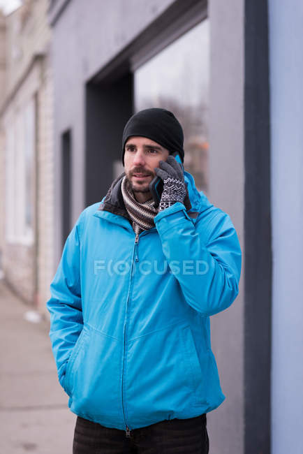 Man talking on mobile phone on town street during winter. — Stock Photo