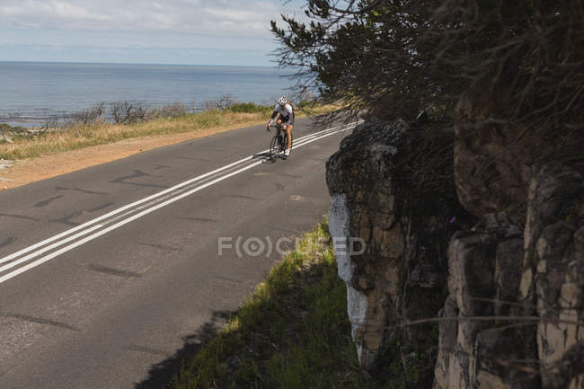 Ciclista montando en bicicleta de montaña en la carretera en un día soleado - foto de stock