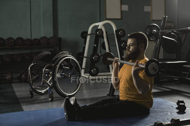 Инвалид упражняется с штангой в тренажерном зале — стоковое фото