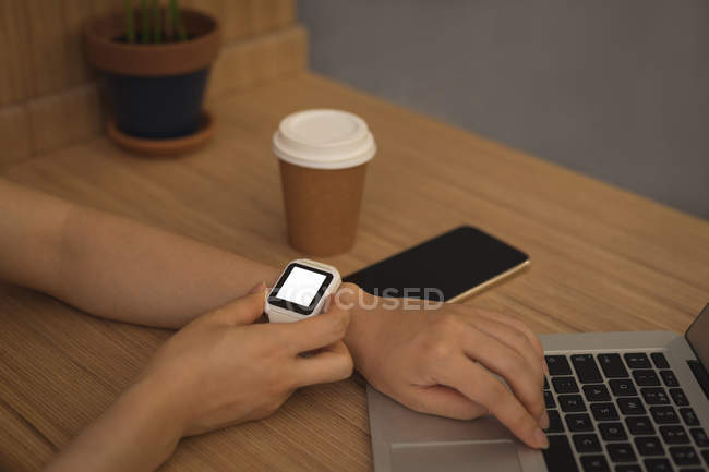 Empresária usando smartwatch na mesa no escritório — Fotografia de Stock