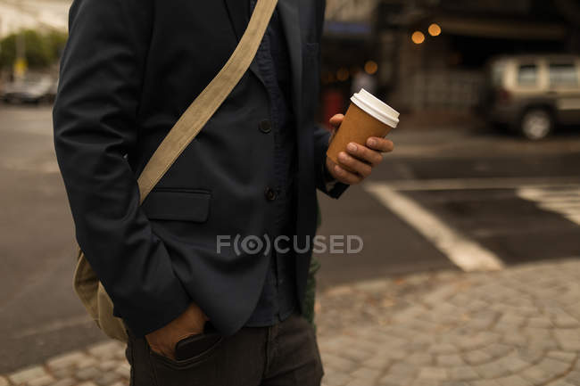 Mid section of businessman holding disposable coffee cup — Stock Photo