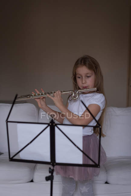 Menina tocando flauta na sala de estar em casa — Fotografia de Stock