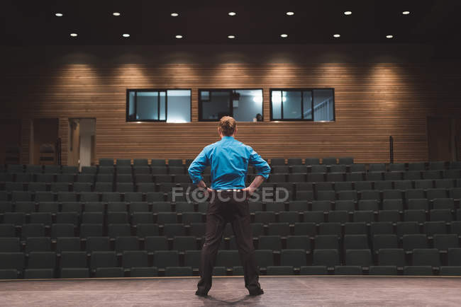 Male actor standing with hands on hips on stage at theatre. — Stock Photo