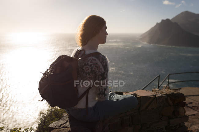 Красивая рыжая женщина сидит на смотровой площадке под солнечным светом — стоковое фото