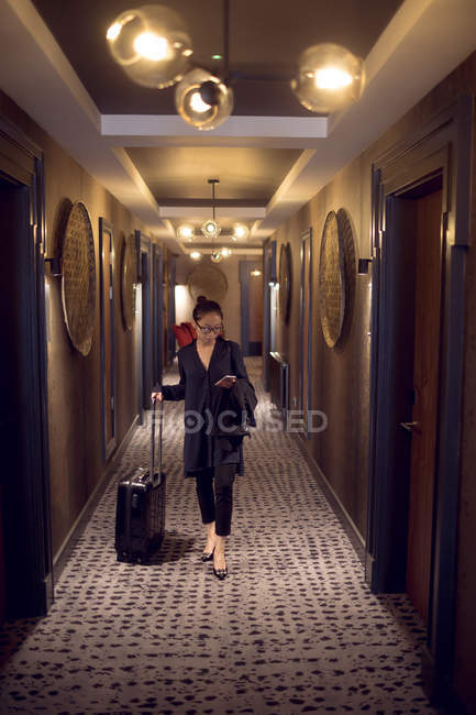 Жінка з сумкою на візку, що йде в коридорі готелю — стокове фото