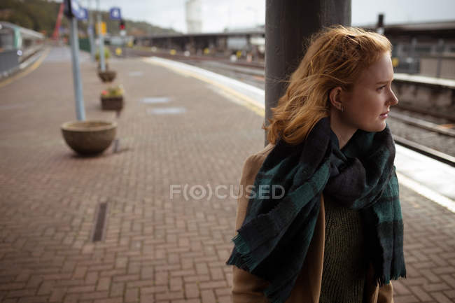 Curious beautiful young woman waiting for train at train platform — Stock Photo