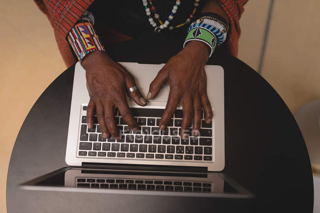 Вид сверху на человека масаи в традиционной одежде с помощью ноутбука — стоковое фото