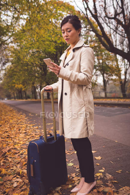 Donna d'affari che utilizza il telefono cellulare in strada durante l'autunno — Foto stock