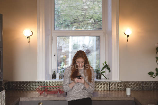 Jeune femme utilisant un téléphone portable à la maison — Photo de stock