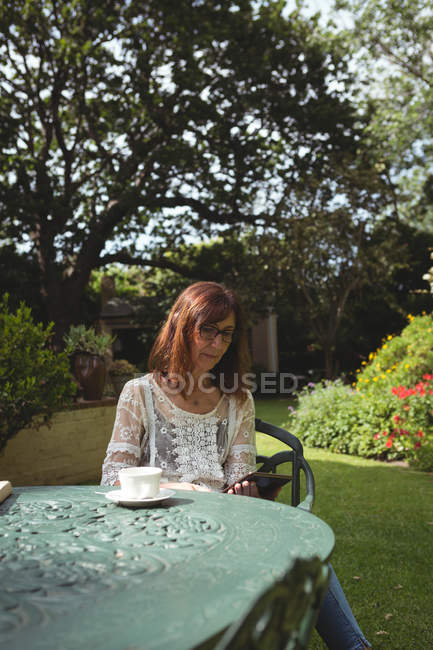 Frau nutzt digitales Tablet am Tisch im Garten — Stockfoto