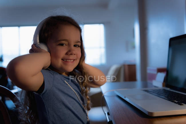 Усміхнена дівчина слухає музику на навушниках вдома — стокове фото