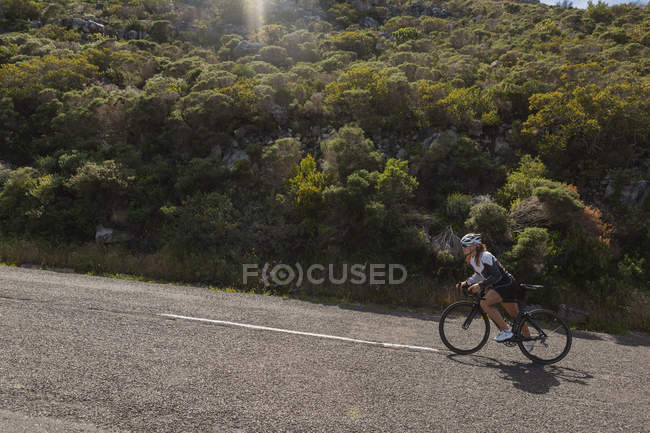 Biker riding mountain bike on road on a sunny day — Stock Photo