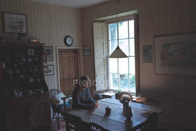 Jovem mulher usando telefone celular em casa — Fotografia de Stock