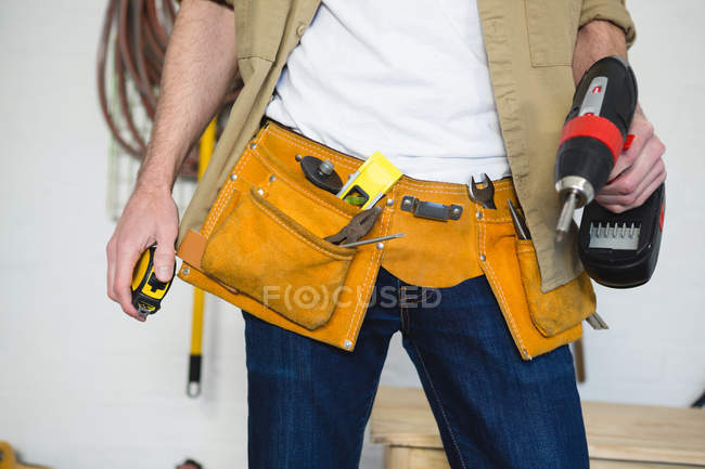 Seção média de carpinteiro masculino com cinto de ferramentas na oficina — Fotografia de Stock