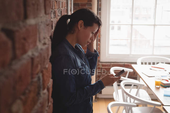 Executivo feminino usando telefone celular no escritório criativo — Fotografia de Stock