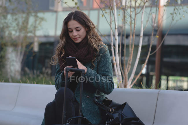 Молода жінка використовує мобільний телефон у сонячний день — стокове фото