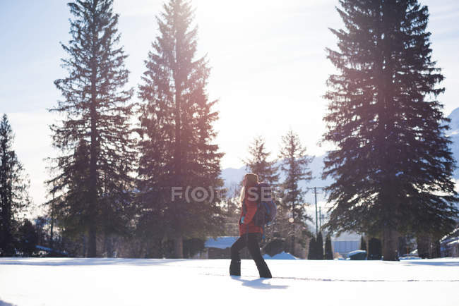 Vista lateral de la mujer caminando sobre el paisaje cubierto de nieve - foto de stock