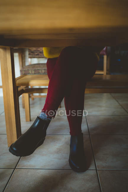 Жінка сидить з ногами, схрещеними на колінах у вітальні вдома — стокове фото