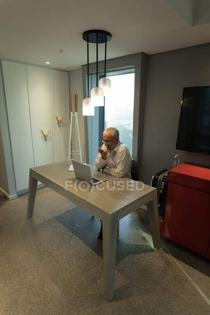Geschäftsmann telefoniert während der Arbeit am Laptop im Hotel — Stockfoto
