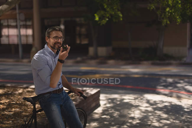 Чоловік розмовляє по мобільному телефону біля вулиці в сонячний день — стокове фото