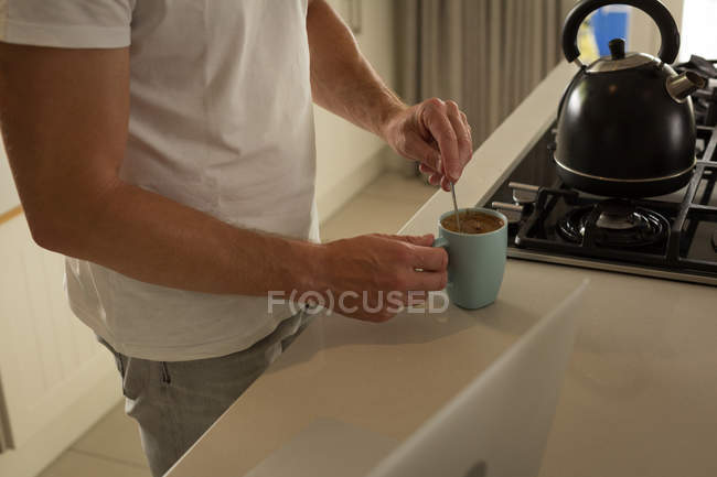 Середина чоловіка готує каву на кухні вдома — стокове фото