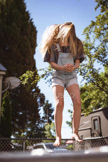 Передпідліткова дівчина стрибає на батуті в саду . — стокове фото