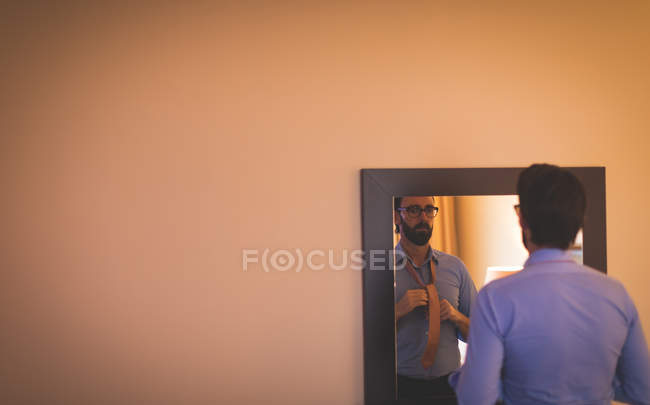 Empresário que se veste em frente ao espelho no quarto de hotel — Fotografia de Stock