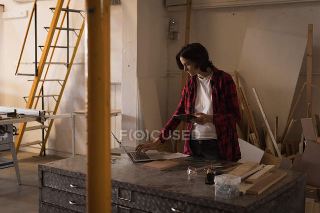 Kunsthandwerkerin benutzt Laptop am Schreibtisch in Werkstatt. — Stockfoto