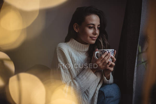 Mulher bonita segurando uma xícara de café em casa — Fotografia de Stock