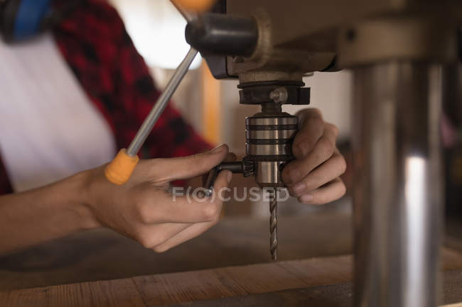 Gros plan de l'artisan femelle vérifiant la perceuse verticale dans l'atelier . — Photo de stock