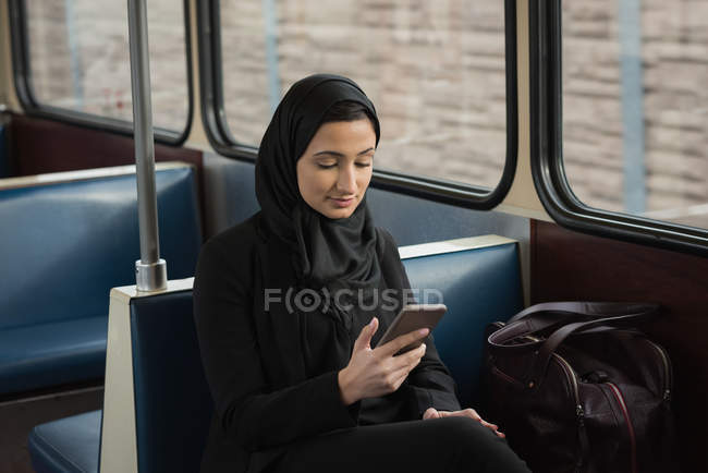 Mujer joven en hijab usando teléfono móvil - foto de stock