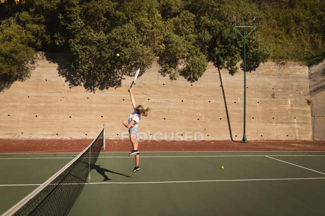 Mulher praticando tênis no campo de tênis em um dia ensolarado — Fotografia de Stock