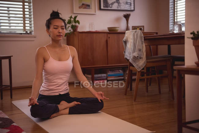 Mulher realizando ioga na sala de estar em casa — Fotografia de Stock