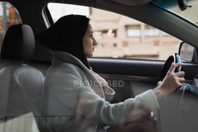Молодая женщина в хиджабе водит машину — стоковое фото