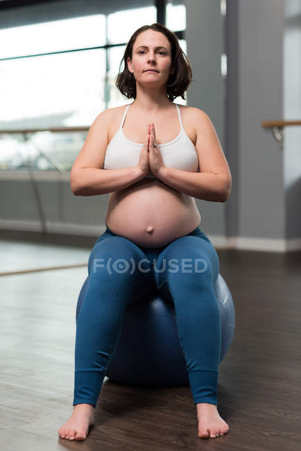 Mujer embarazada realizando yoga sobre pelota de ejercicio - foto de stock