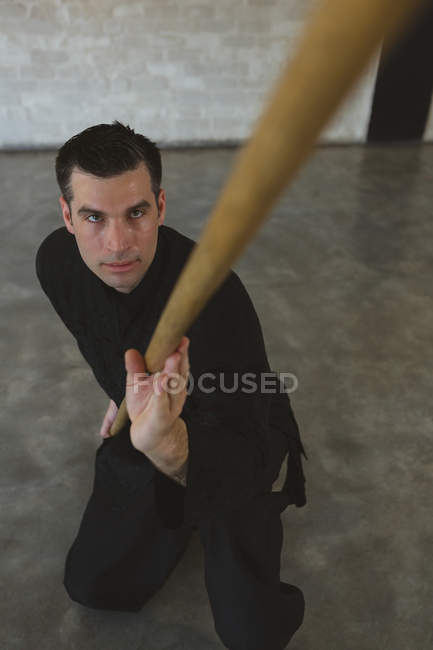 Combattant de kung fu pratiquant avec un long poteau dans un studio de fitness . — Photo de stock