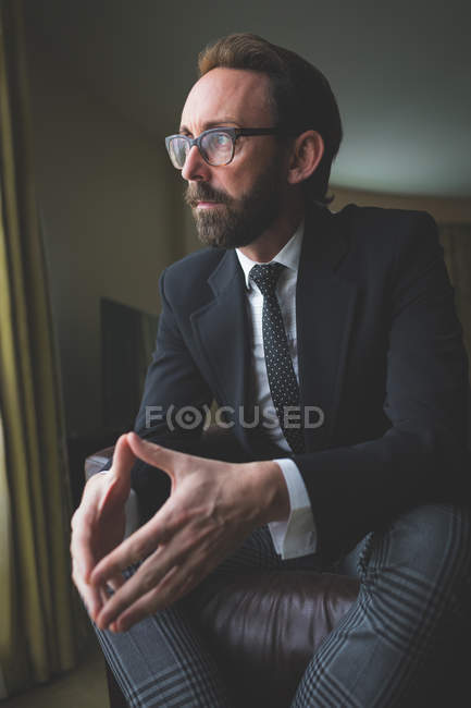 Nachdenklicher Geschäftsmann sitzt auf Sessel im Hotelzimmer — Stockfoto