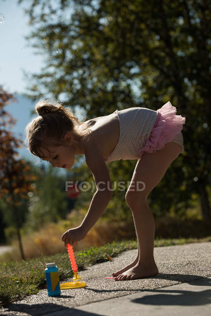Menina bonito jogando com varinha de bolha no parque — Fotografia de Stock