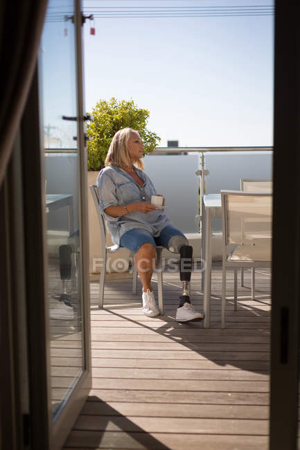 Donna disabile che beve caffè in balcone a casa . — Foto stock