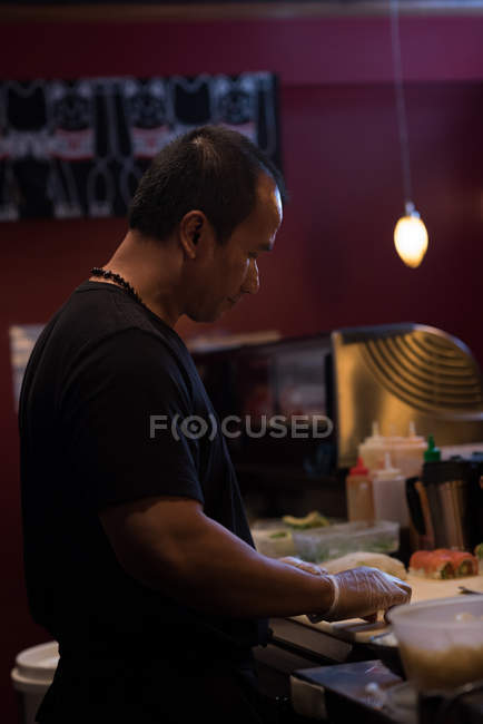Chef rolando sushi desenrolado em uma cozinha restaurante — Fotografia de Stock