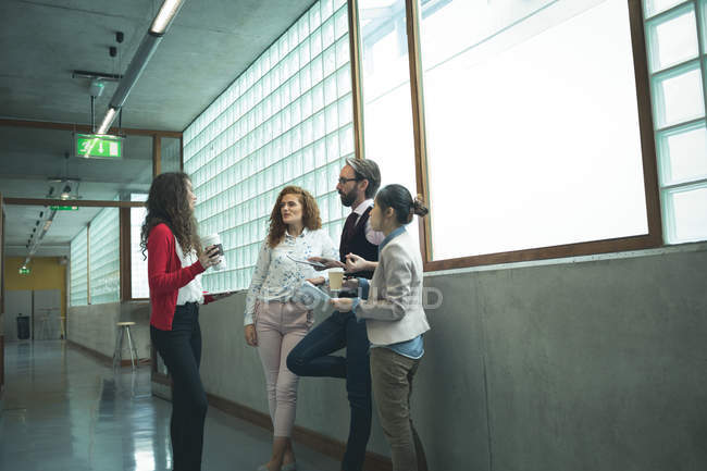 Executives discussing with each other at office corridor — Stock Photo