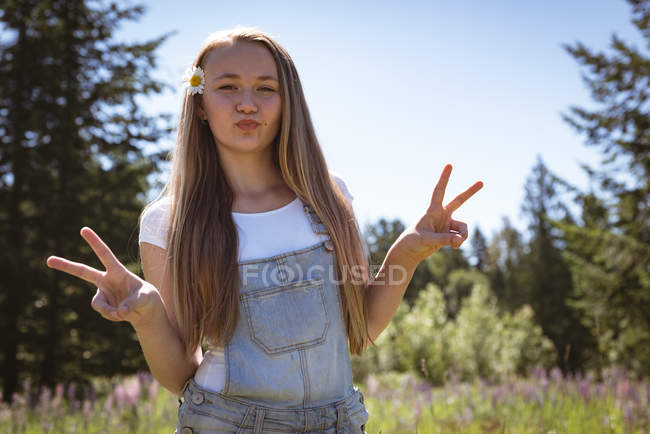 Retrato de chica mostrando signo v en el campo en verano . - foto de stock