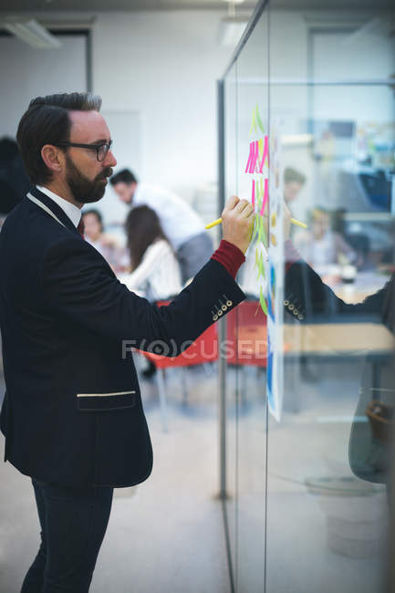 Бизнес-руководитель пишет на липких бумажках в офисе — стоковое фото