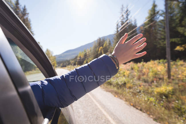 Woman waving her hand out of car window while travelling — Stock Photo