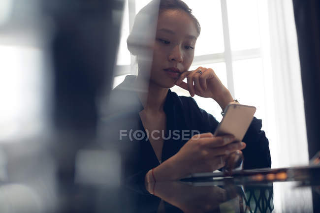 Женщина за столом в отеле с помощью мобильного телефона — стоковое фото